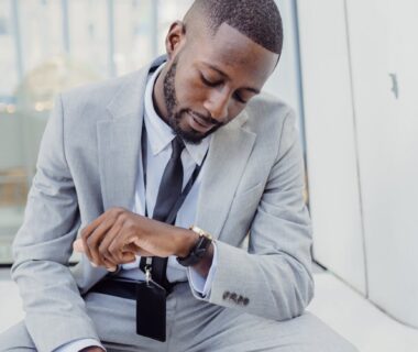 elegant office worker wearing a suit sitting and looking at his watch