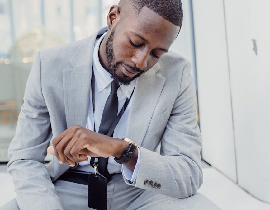 elegant office worker wearing a suit sitting and looking at his watch