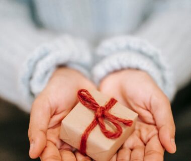 crop faceless woman showing small gift box on palms