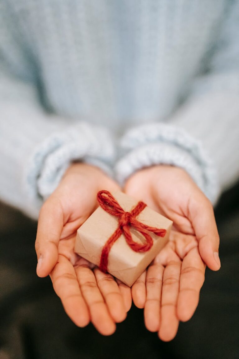 crop faceless woman showing small gift box on palms