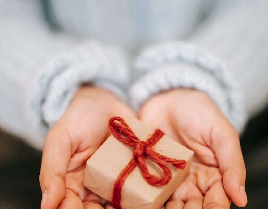 crop faceless woman showing small gift box on palms