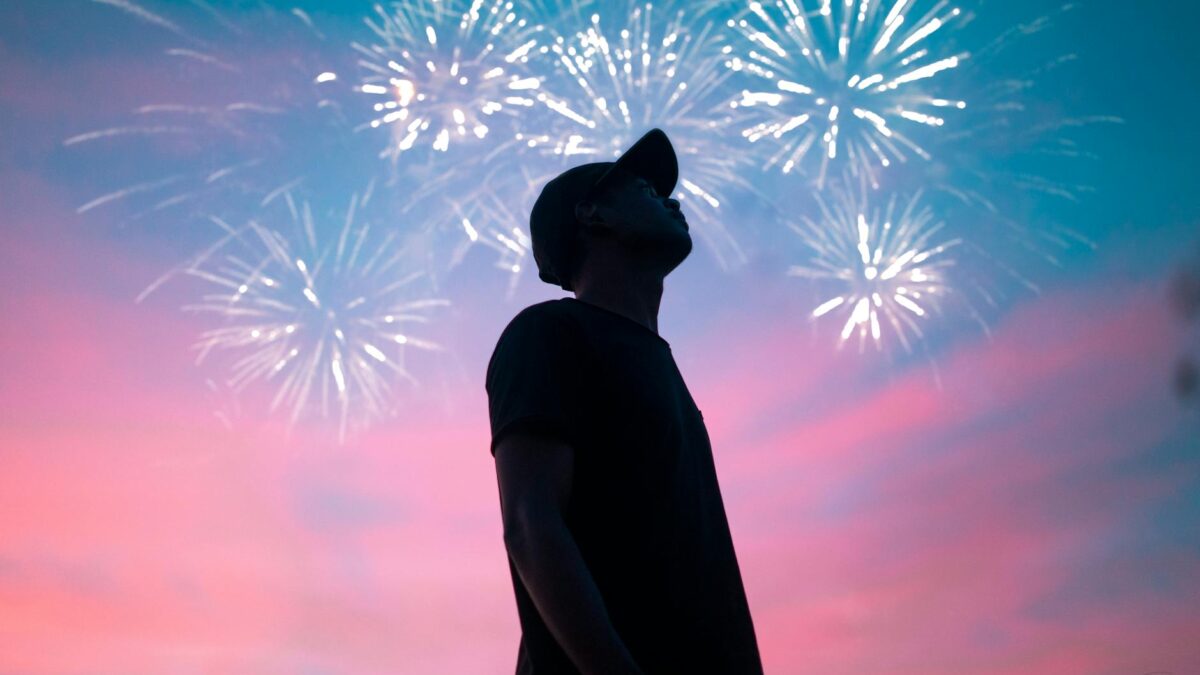 man in black t shirt standing under beautiful sky with fireworks