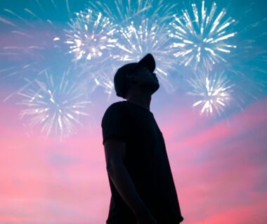 man in black t shirt standing under beautiful sky with fireworks