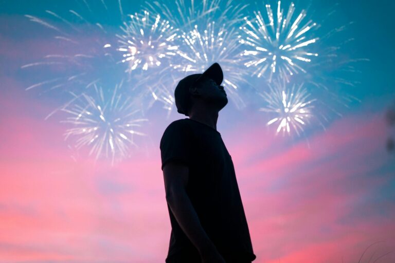 man in black t shirt standing under beautiful sky with fireworks